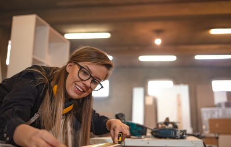 Une femme dans un atelier de menuiserie prend des mesures avec un mètre ruban