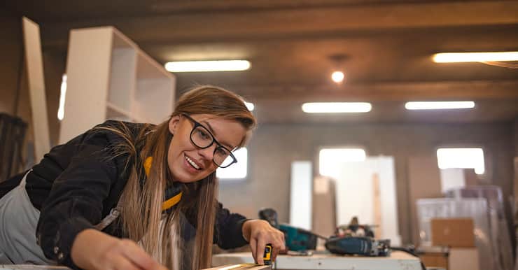 Une femme dans un atelier de menuiserie prend des mesures avec un mètre ruban