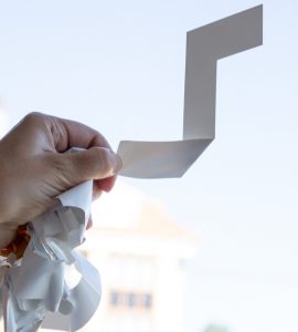 Gros plan sur une main enlevant un autocollant sur la vitre d'une fenêtre