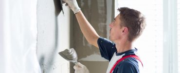 Un homme applique un cimentage sur le mur à l'aide de ces spatules