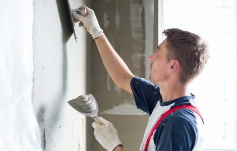 Un homme applique un cimentage sur le mur à l'aide de ces spatules