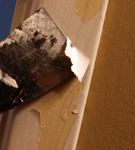 Gros plan sur une personne décapant de la peinture avec une spatule