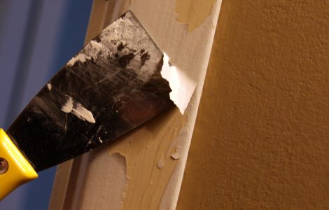 Gros plan sur une personne décapant de la peinture avec une spatule