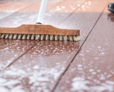 Focus sur une brosse à laver pendant le nettoyage d’une terrasse en bois