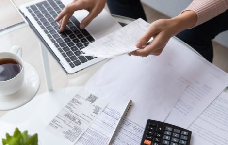 Vue de dessus d'une femme calculant des factures en utilisant un ordinateur portable