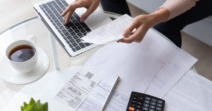 Vue de dessus d'une femme calculant des factures en utilisant un ordinateur portable