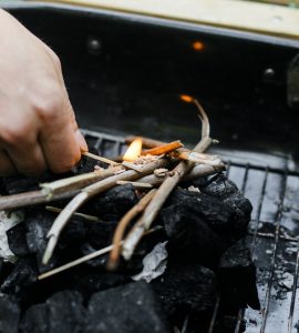Un homme commence à allumer du charbon de bois pour le barbecue