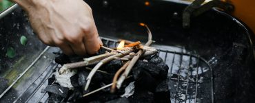 Un homme commence à allumer du charbon de bois pour le barbecue