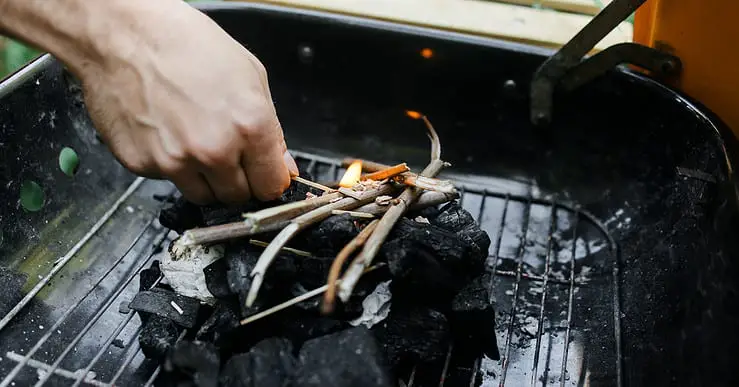 Un homme commence à allumer du charbon de bois pour le barbecue