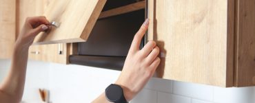 Zoom sur les mains d’une femme ouvrant un placard de cuisine en bois