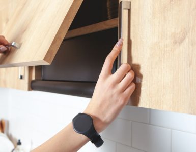 Zoom sur les mains d’une femme ouvrant un placard de cuisine en bois
