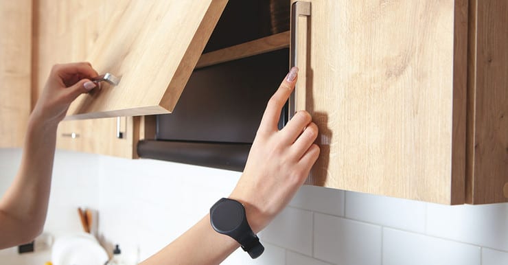 Zoom sur les mains d’une femme ouvrant un placard de cuisine en bois