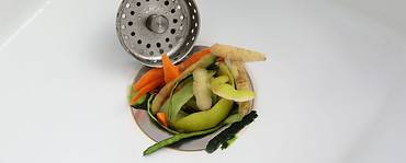 Zoom sur un évier de cuisine bouché par des épluchures de légumes