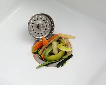 Zoom sur un évier de cuisine bouché par des épluchures de légumes