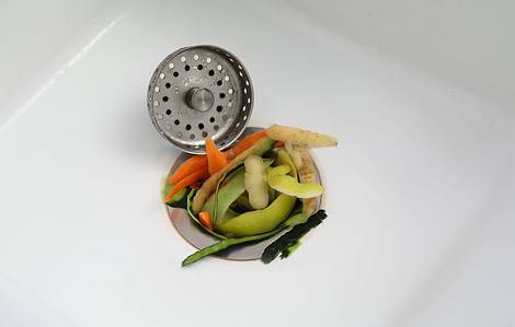 Zoom sur un évier de cuisine bouché par des épluchures de légumes