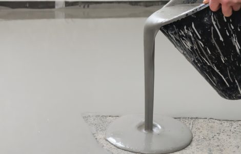 Un homme verse un mélange de ciment sur le sol