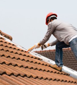 Un homme utilise un pistolet à calfeutrage pour sceller une fuite sur le toit