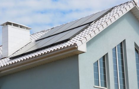 Une maison gris avec des panneaux solaires sur le toit en tuile
