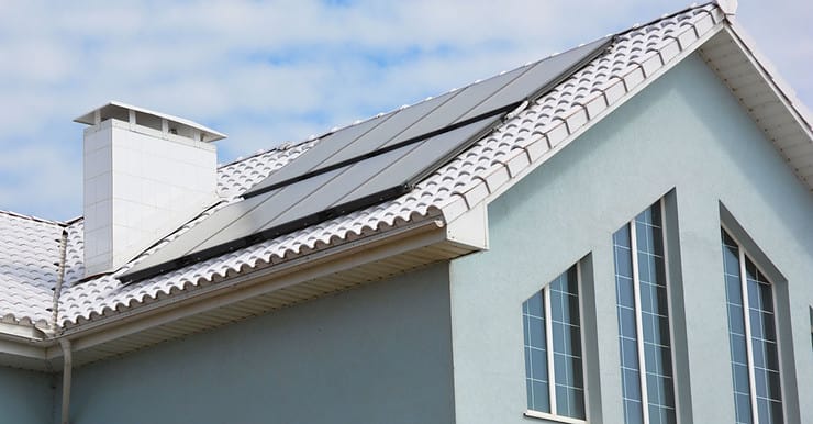 Une maison gris avec des panneaux solaires sur le toit en tuile