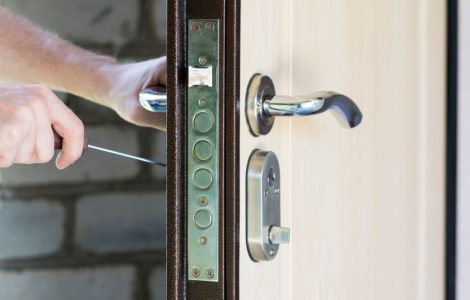 Un homme répare la serrure renforcée de sa porte à l’aide d’un tournevis