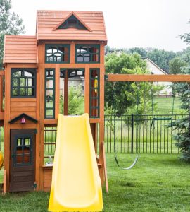 Une structure de jeu en bois avec glissoire et balancier dans un jardin
