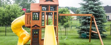 Une structure de jeu en bois avec glissoire et balancier dans un jardin