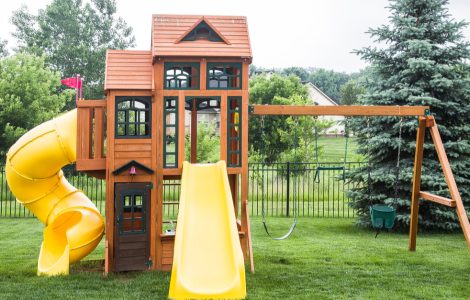Une structure de jeu en bois avec glissoire et balancier dans un jardin