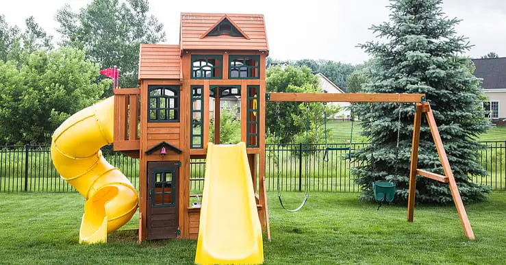 Une structure de jeu en bois avec glissoire et balancier dans un jardin