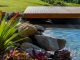 Une piscine naturelle dans un jardin avec un petit pont en bois