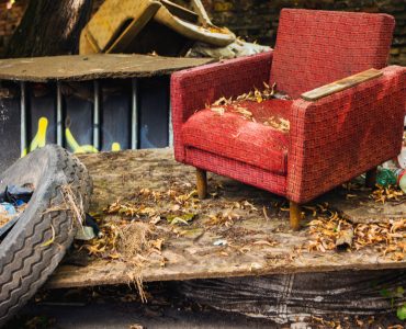 Un vieux fauteuil rouge et un pneu de voiture laissés dans la rue