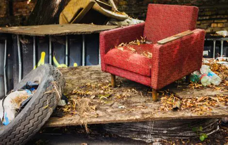 Un vieux fauteuil rouge et un pneu de voiture laissés dans la rue