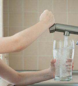 Une petite fille remplit un verre avec de l'eau du robinet