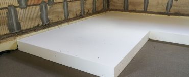Travaux d'isolation thermique par pose de feuille de polystyrène expansé sur le sol en béton