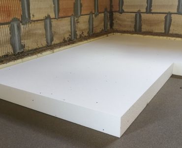 Travaux d'isolation thermique par pose de feuille de polystyrène expansé sur le sol en béton