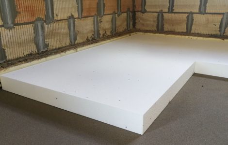 Travaux d'isolation thermique par pose de feuille de polystyrène expansé sur le sol en béton