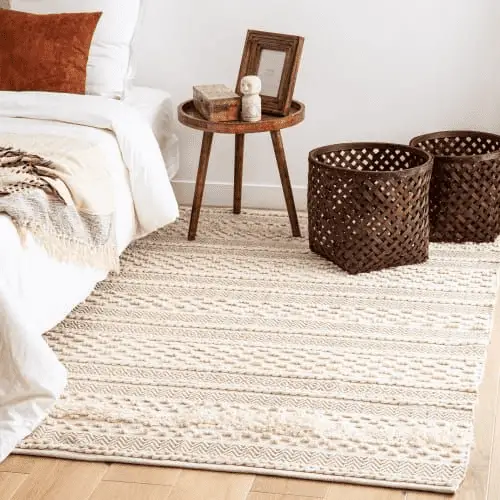 Un tapis crème aux motifs ethniques en ton sur ton pour ajouter de la texture dans une chambre à la déco neutre et épurée