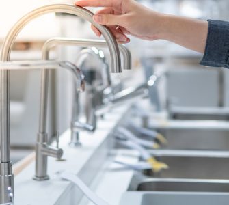 Une personne choisissant un évier dans un magasin touche le robinet