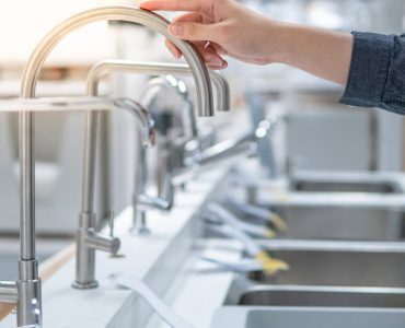 Une personne choisissant un évier dans un magasin touche le robinet