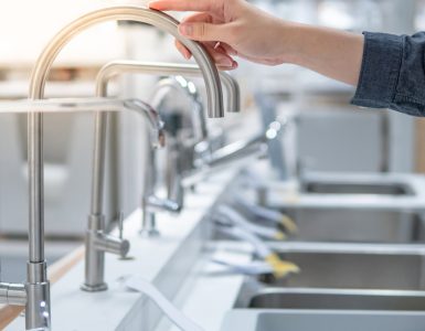 Une personne choisissant un évier dans un magasin touche le robinet