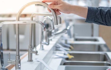 Une personne choisissant un évier dans un magasin touche le robinet