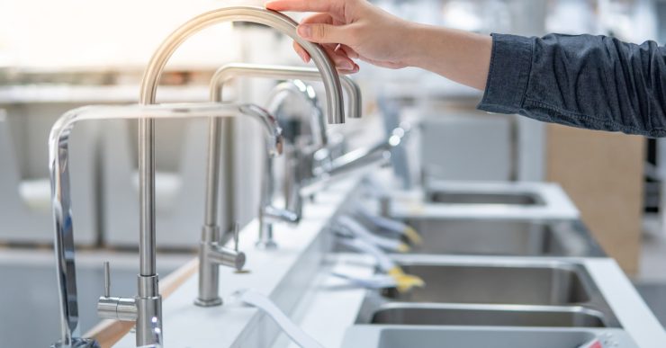 Une personne choisissant un évier dans un magasin touche le robinet