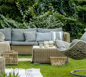 Mobilier en osier avec des coussins gris placés dans le jardin