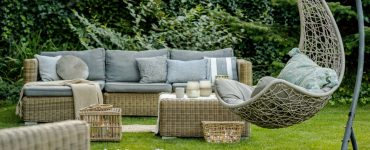 Mobilier en osier avec des coussins gris placés dans le jardin