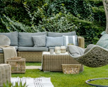 Mobilier en osier avec des coussins gris placés dans le jardin