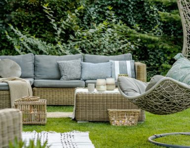 Mobilier en osier avec des coussins gris placés dans le jardin