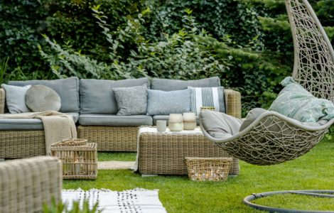 Mobilier en osier avec des coussins gris placés dans le jardin