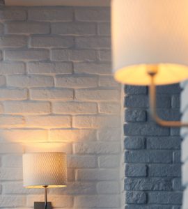 Lampes murales allumées, fixées sur un mur en briques