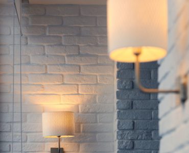 Lampes murales allumées, fixées sur un mur en briques