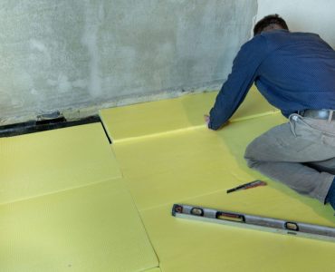 Un homme installe du polystyrène expansé dans une pièce pour l'isolation du sol