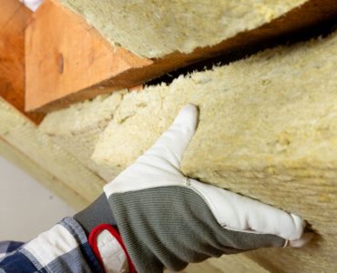 Zoom sur la main d'un homme en train de poser un isolant au plafond